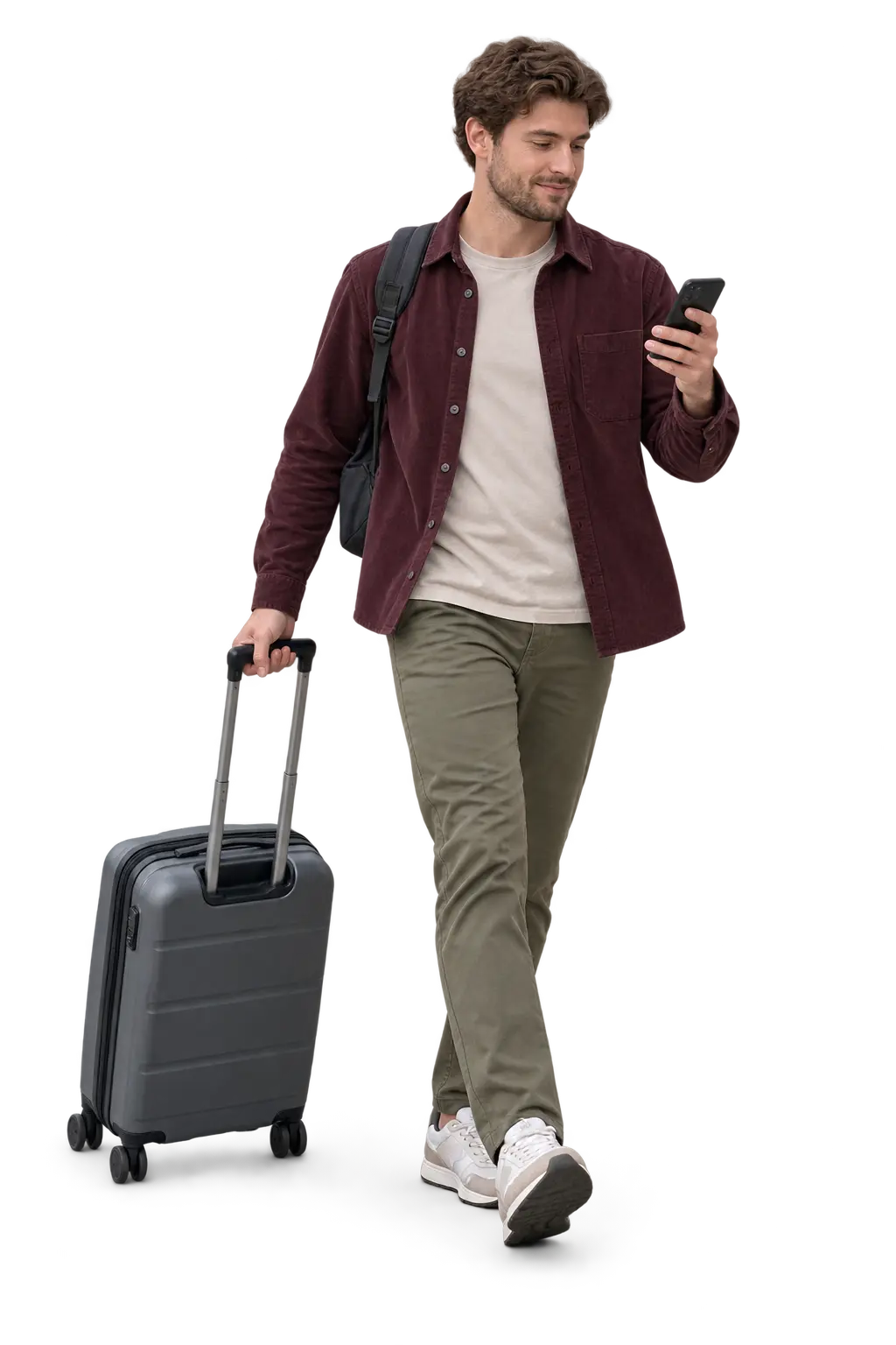 Traveller checking his phone while pulling a grey suitcase