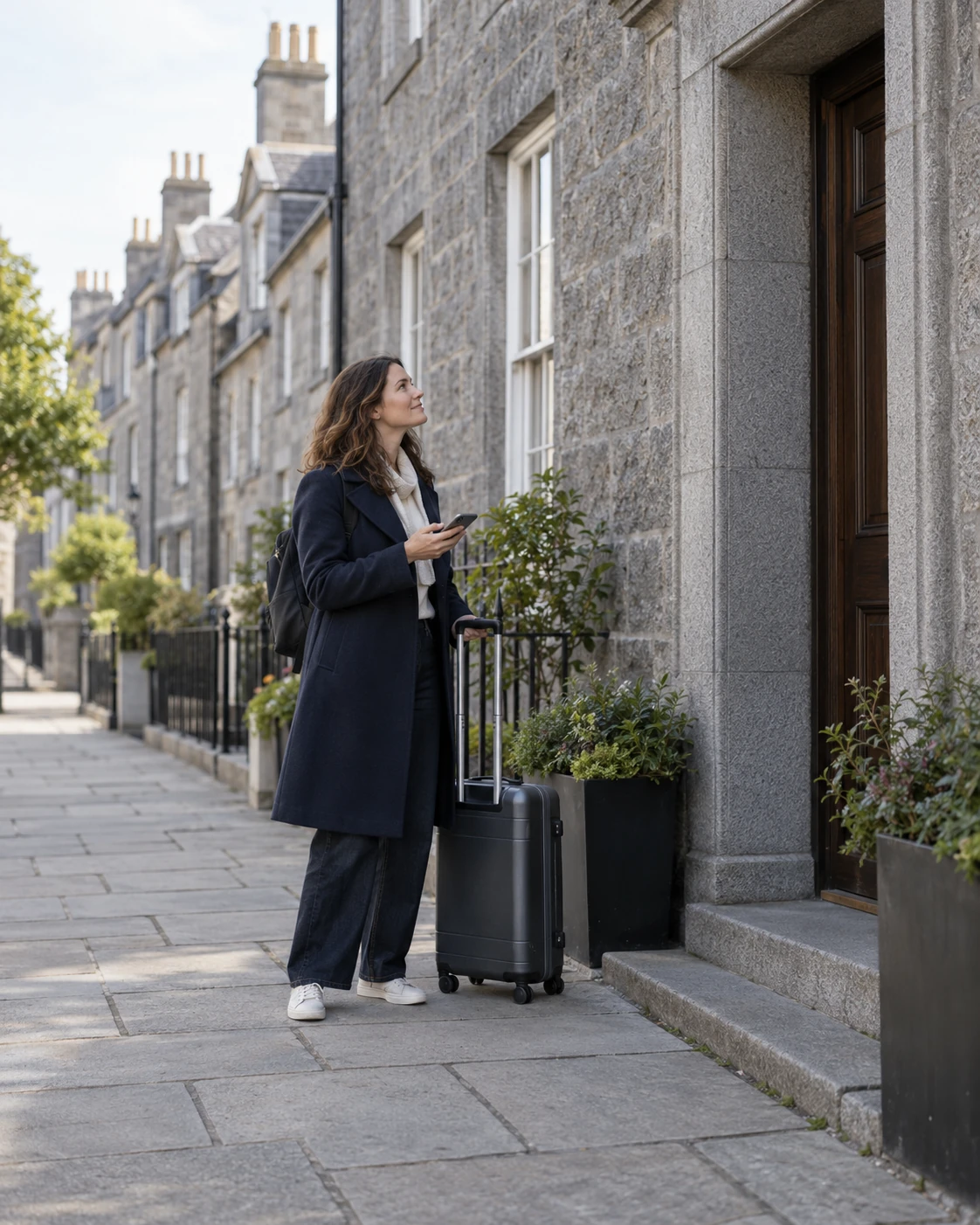 Traveller with a suitcase checking a granite accommodation entrance in Aberdeen