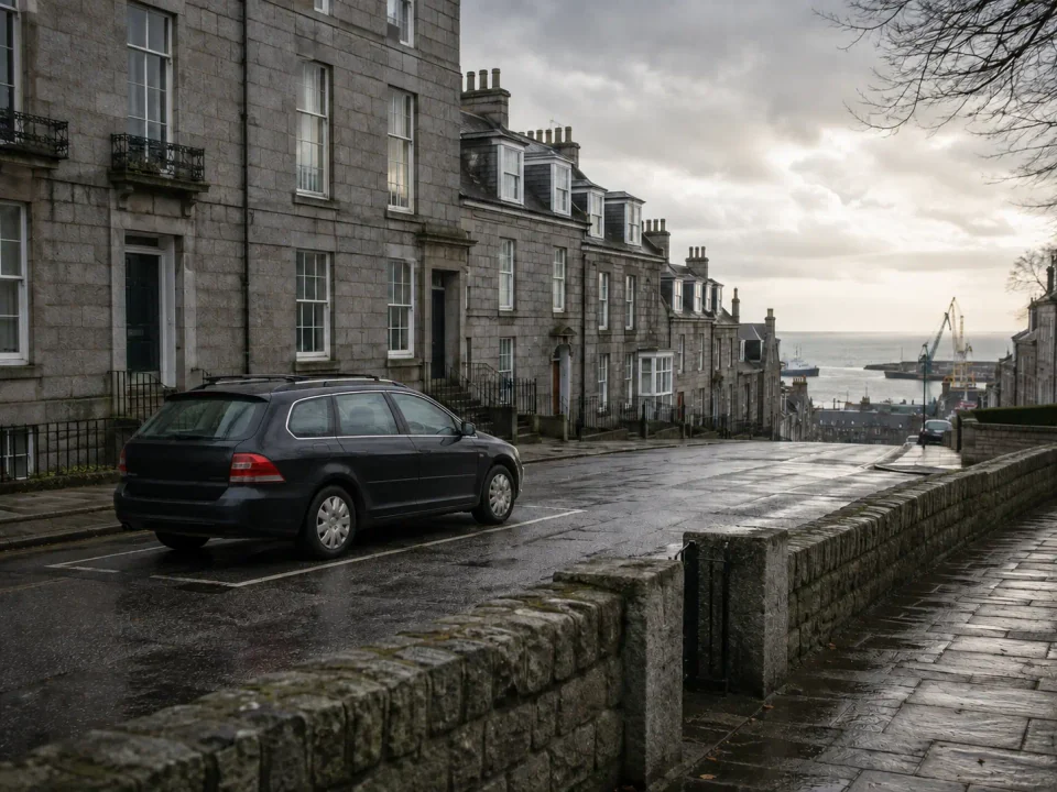 Airport transfer vehicle parked on a wet granite street overlooking Aberdeen harbour