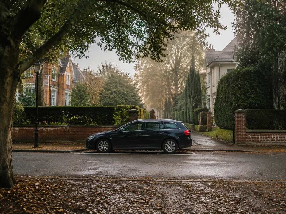 Airport transfer vehicle parked on a leafy residential avenue in Ascot