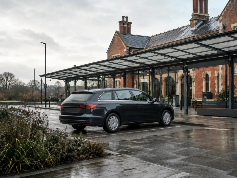 Airport transfer vehicle waiting beside brick and glass transport architecture in Ashford, Kent