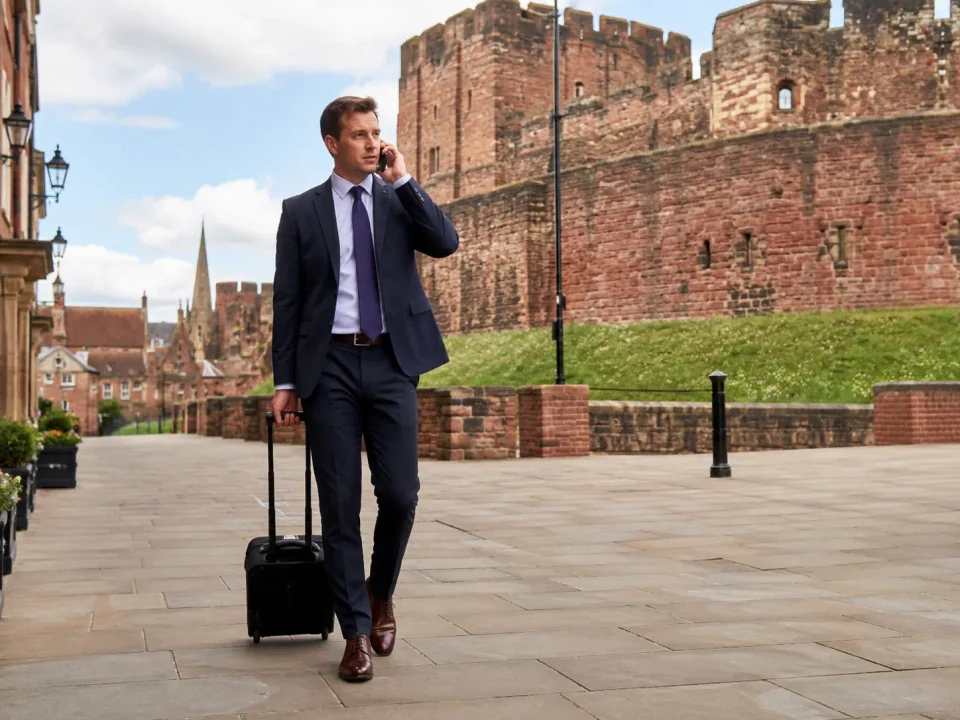 Business traveller making a phone call beside the red sandstone walls of Carlisle Castle