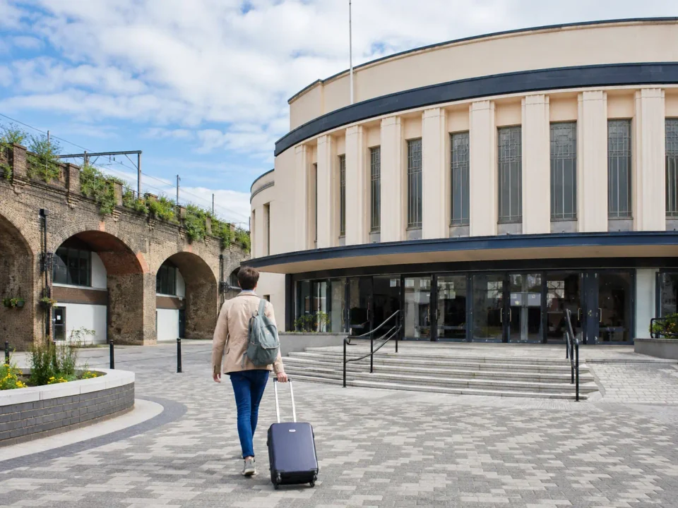 Traveller with a suitcase approaching the curved Art Deco theatre in Catford