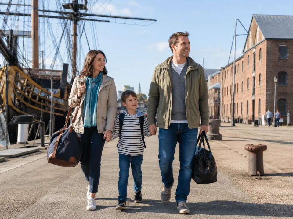 Family carrying travel bags through the maritime setting of Chatham Historic Dockyard