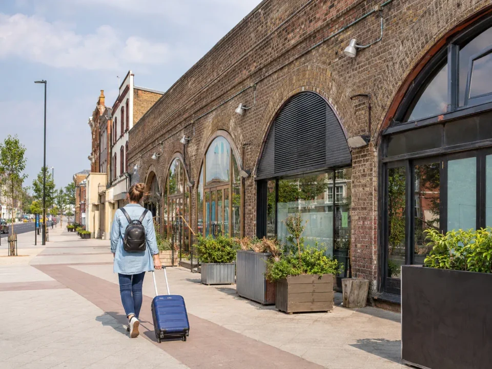 Traveller pulling a suitcase past the brick railway arches in Cricklewood