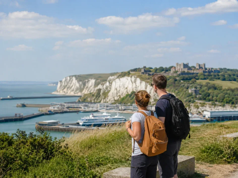 Travellers overlooking Dover harbour, white cliffs and the castle