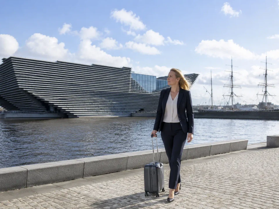 Business traveller with luggage on Dundee waterfront beside the angular museum