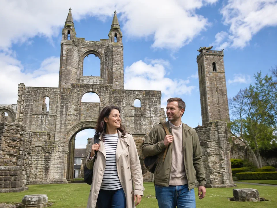 Visitors walking beside the historic stone ruins of Dunfermline Abbey