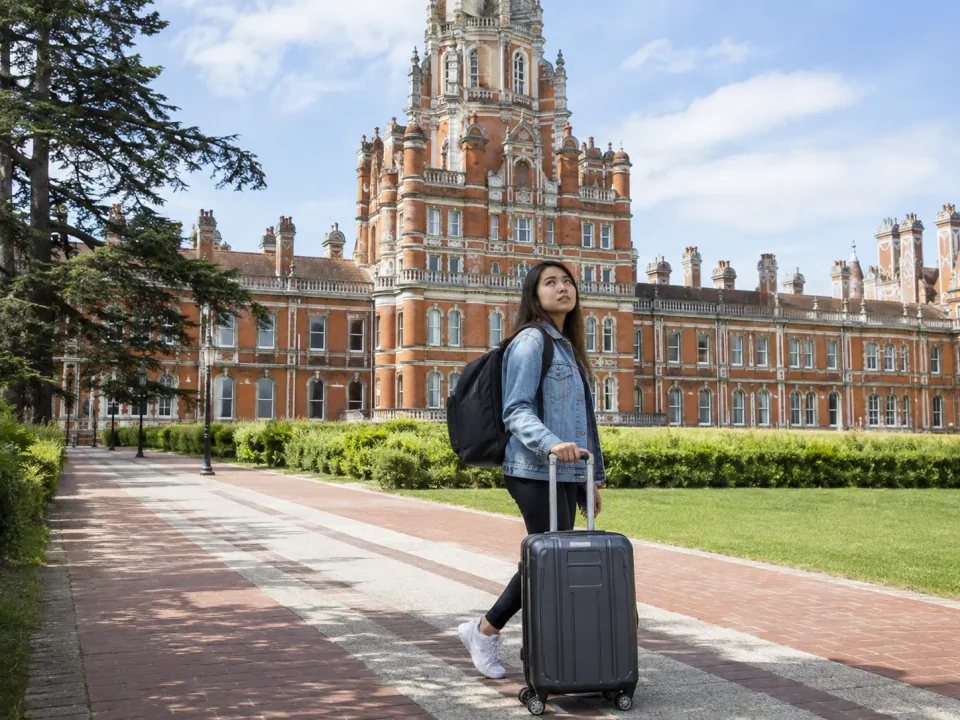 Student traveller with luggage outside Royal Holloway in Egham
