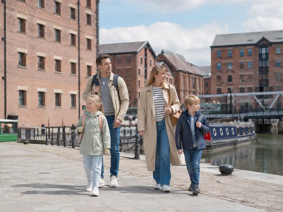 Family travellers walking beside the historic warehouses and canal boats of Gloucester Docks
