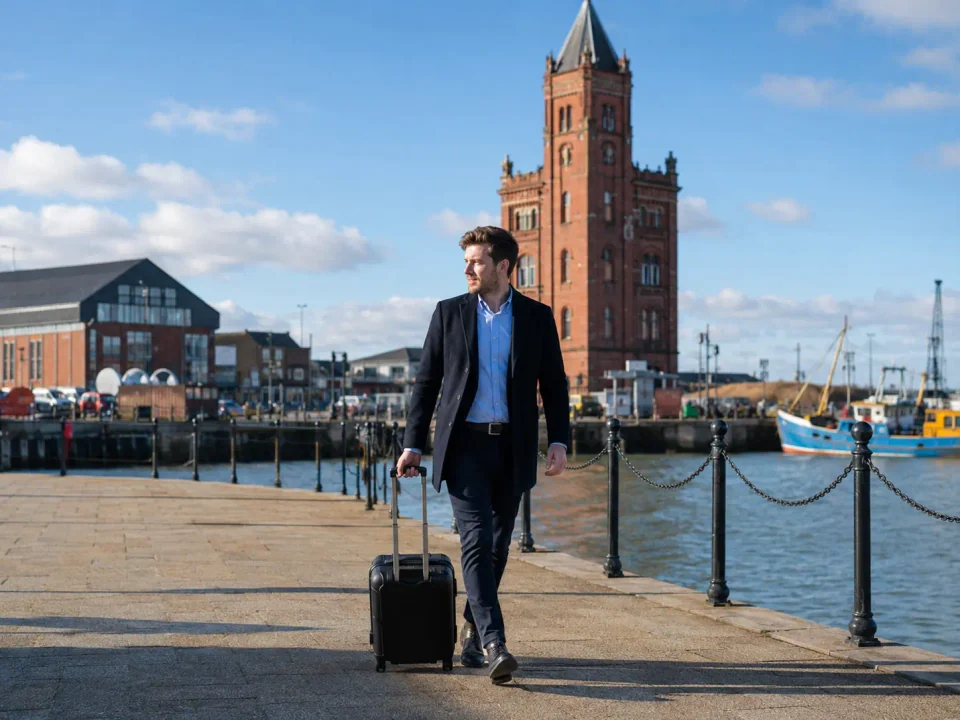 Business traveller with a suitcase beside the dock tower in Grimsby