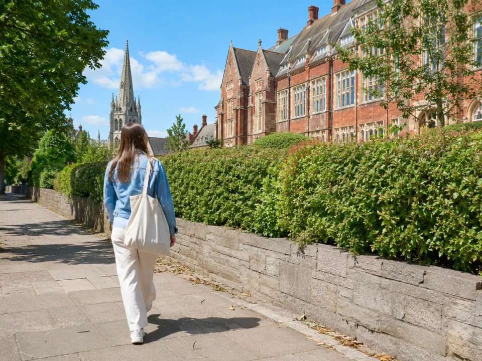 Visitor walking past historic school buildings and a church spire in Harrow-on-the-Hill