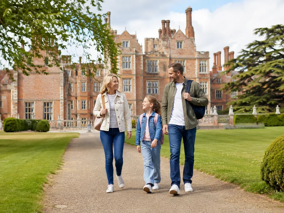 Family visitors walking through the gardens in front of Hatfield House