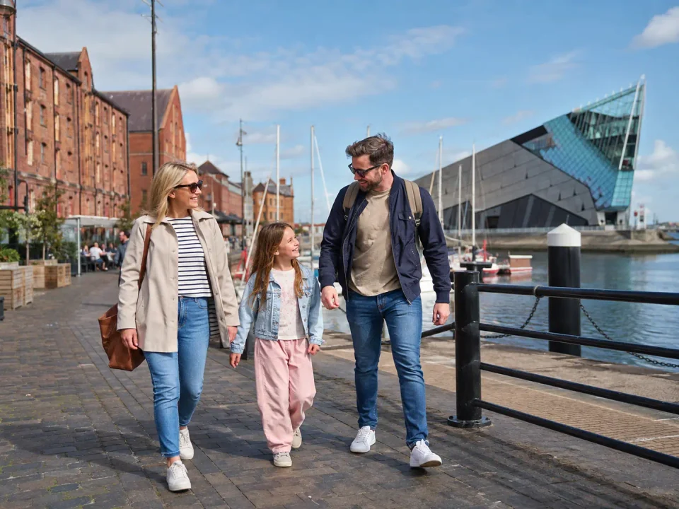 Family visitors walking beside Hull marina and the modern waterfront aquarium