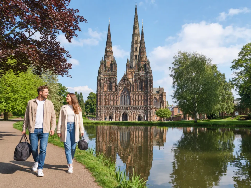 Couple with weekend bags beside Minster Pool and Lichfield Cathedral