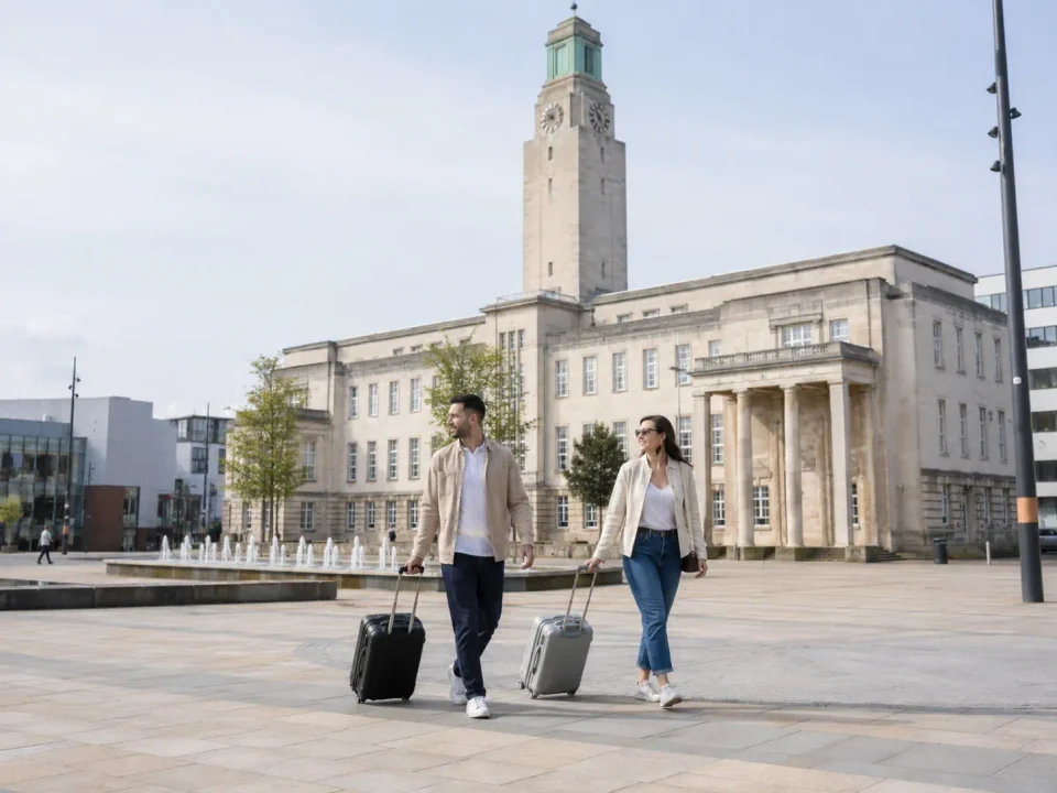 Travellers with luggage crossing the civic square outside Luton Town Hall