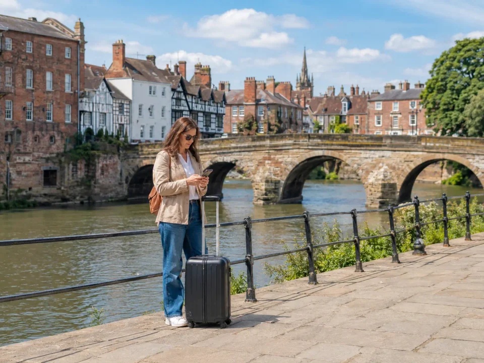 Woman traveller with a suitcase beside the River Severn and historic Shrewsbury