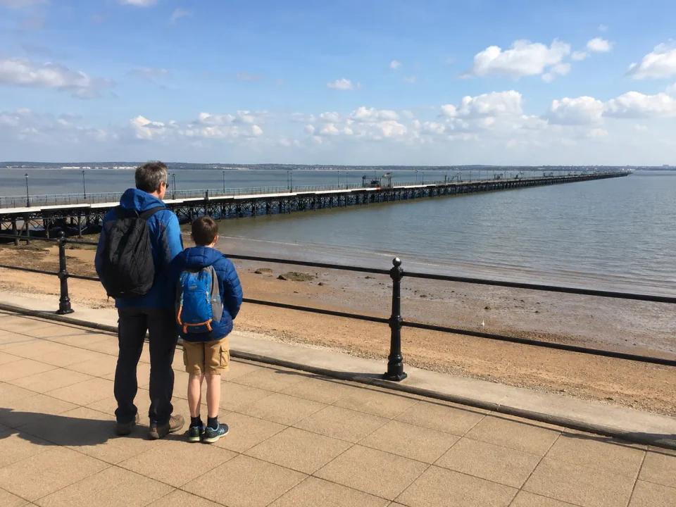 Parent and child overlooking Southend Pier from the seafront promenade