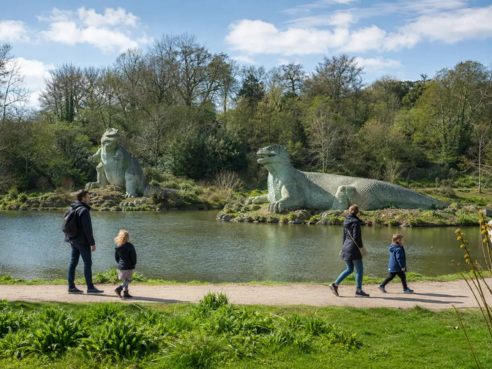 Family visitors walking beside the dinosaur sculptures in Crystal Palace Park, Sydenham