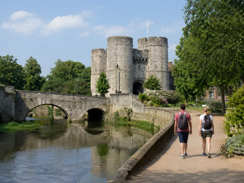 Travelling couple walking beside the River Medway towards Tonbridge Castle