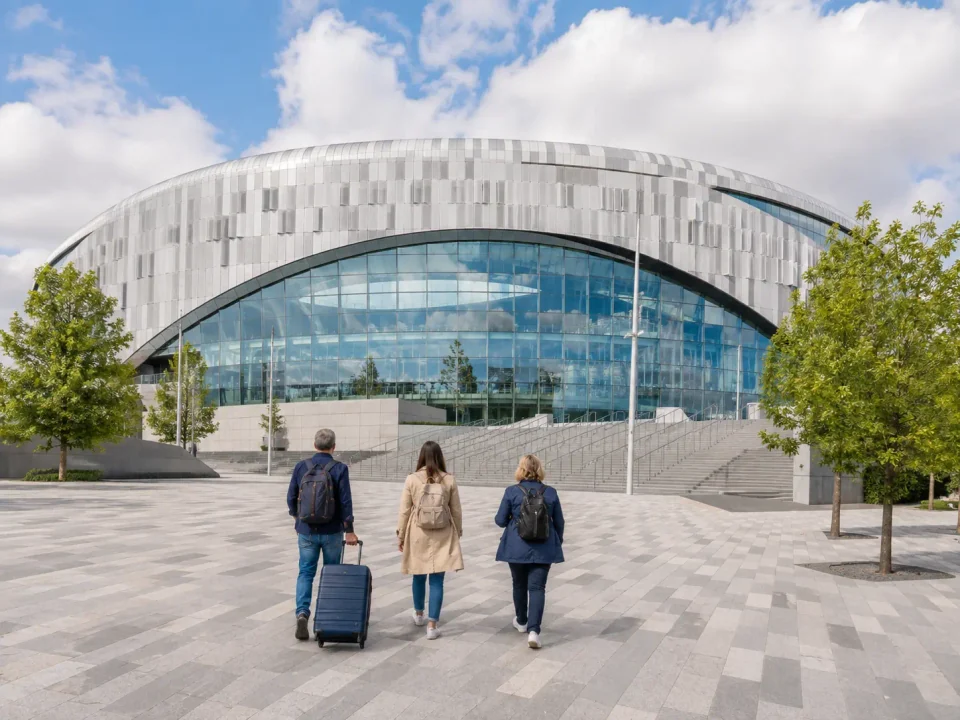 Visitors with luggage crossing the plaza towards the modern stadium in Tottenham