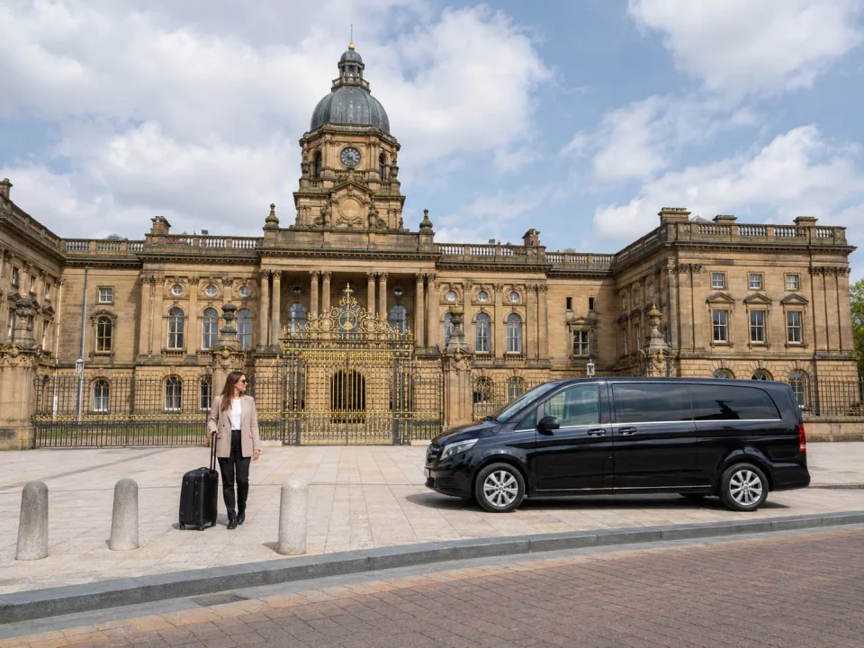 Business traveller with luggage beside a premium van outside Warrington Town Hall