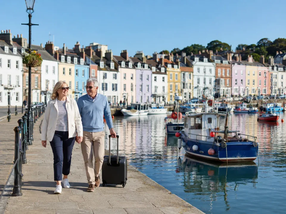 Travelling couple walking beside the colourful harbour in Weymouth
