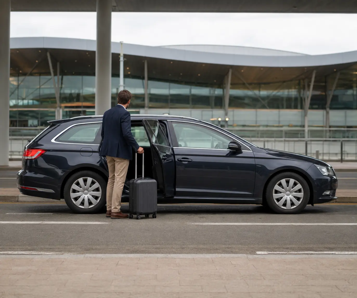 Traveller with luggage beside an estate car at an airport frontage