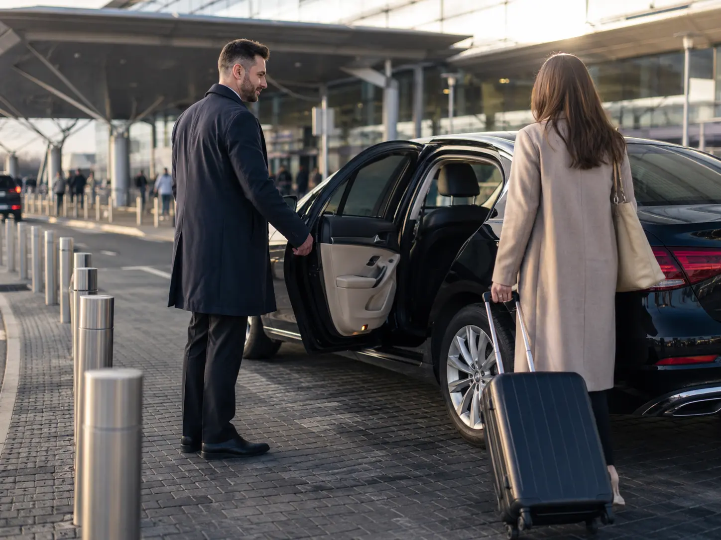 Driver opening an airport transfer car door for an arriving traveller