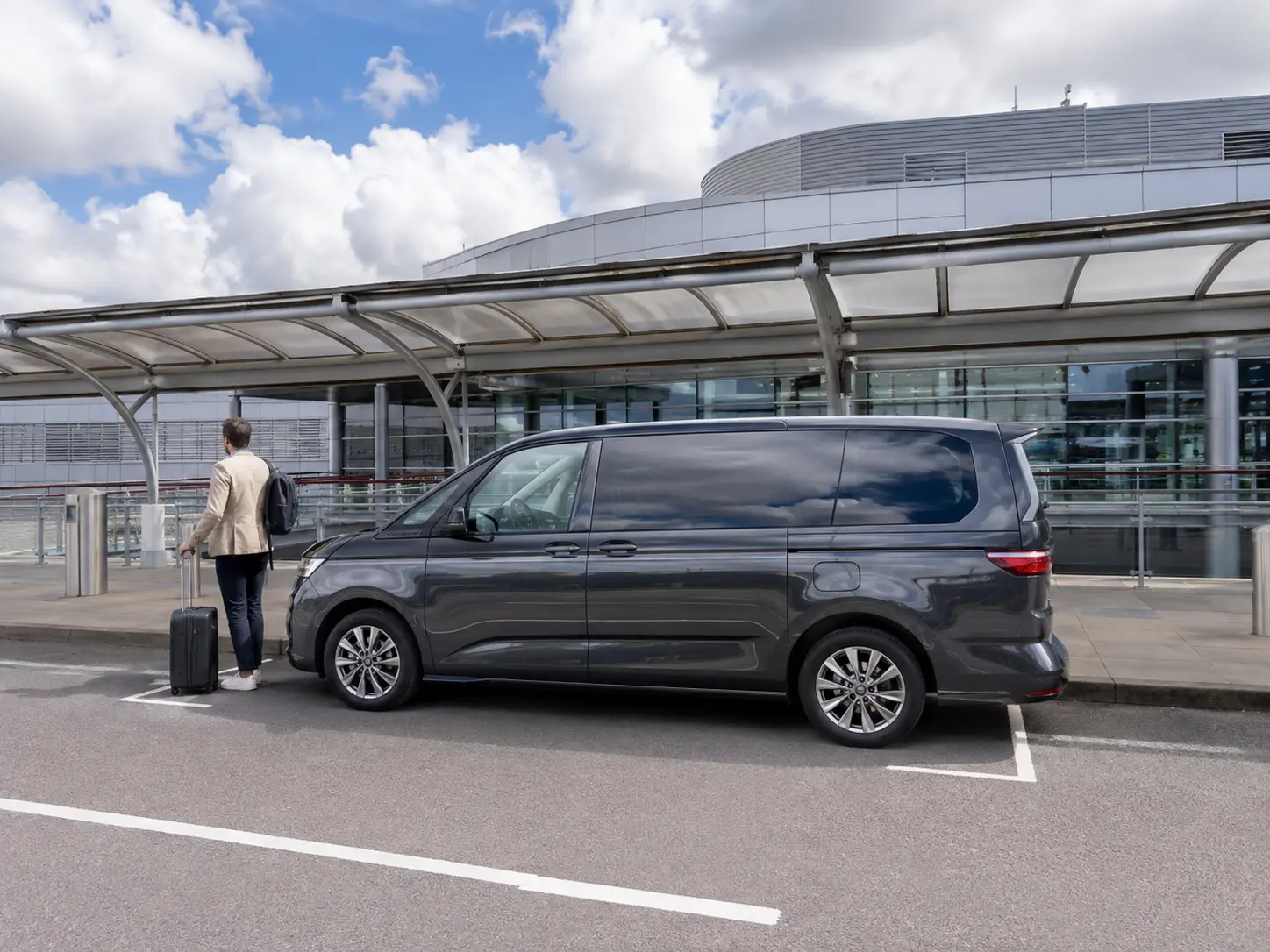 Traveller beside a premium people carrier outside London Luton Airport