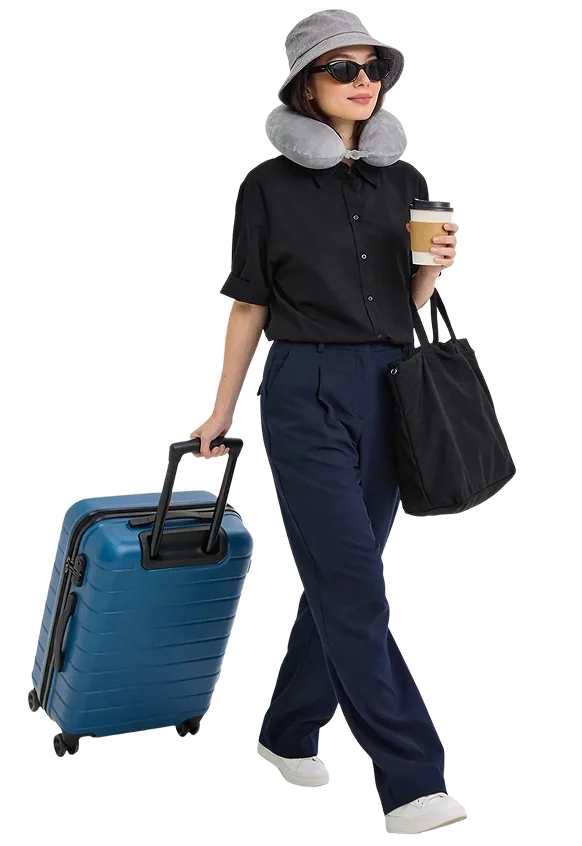A traveler walking with a blue suitcase and black tote bag.