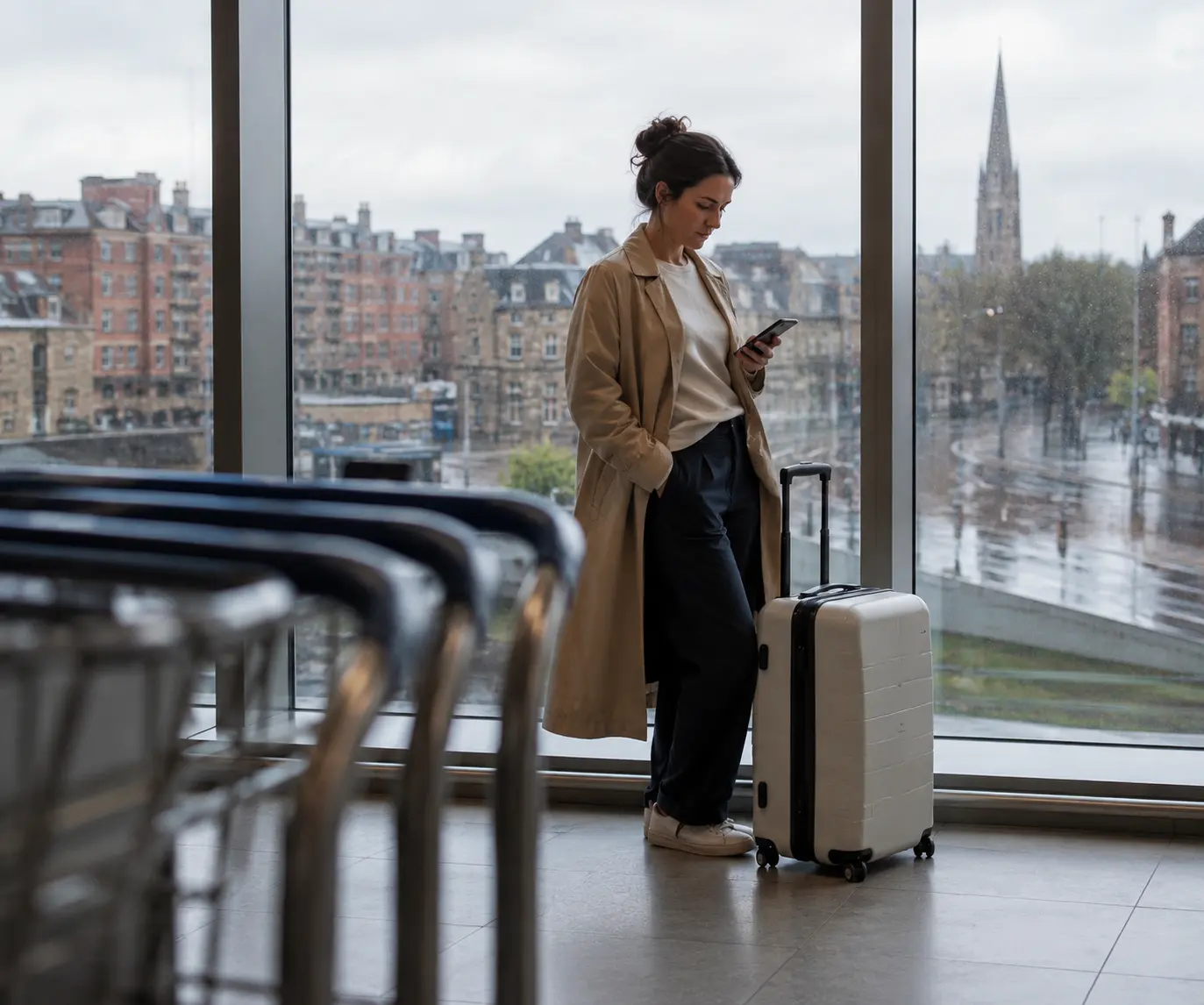 Traveller plans onward city travel on a phone beside a suitcase